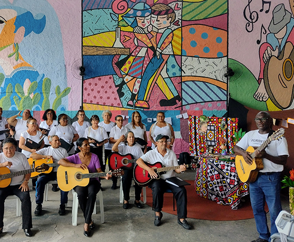 Grupo tocando violão em frente a mural colorido no Espaço Cultural OIAEU
