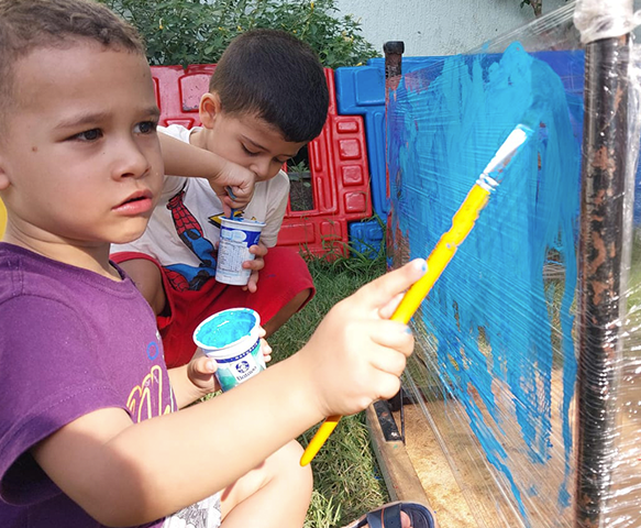Crianças pintando em atividade do CEI OIAEU
